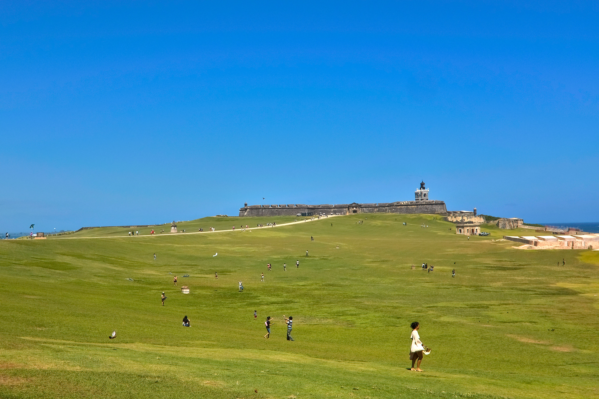 People fly kites in front of El Morro