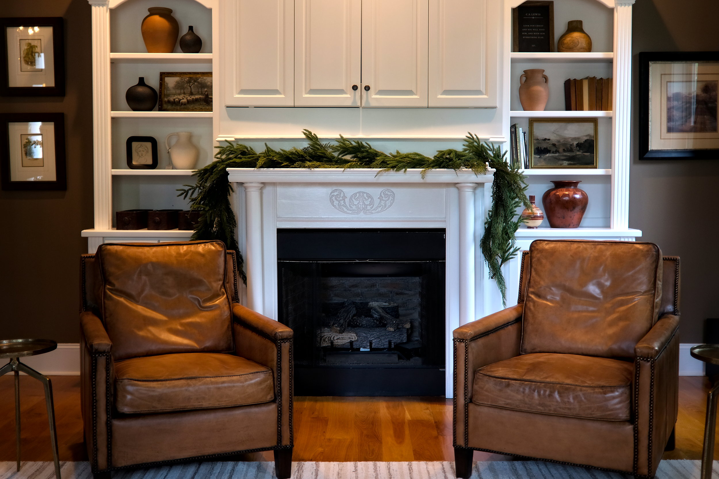 A cozy living room with a fireplace and a pair of leather chairs