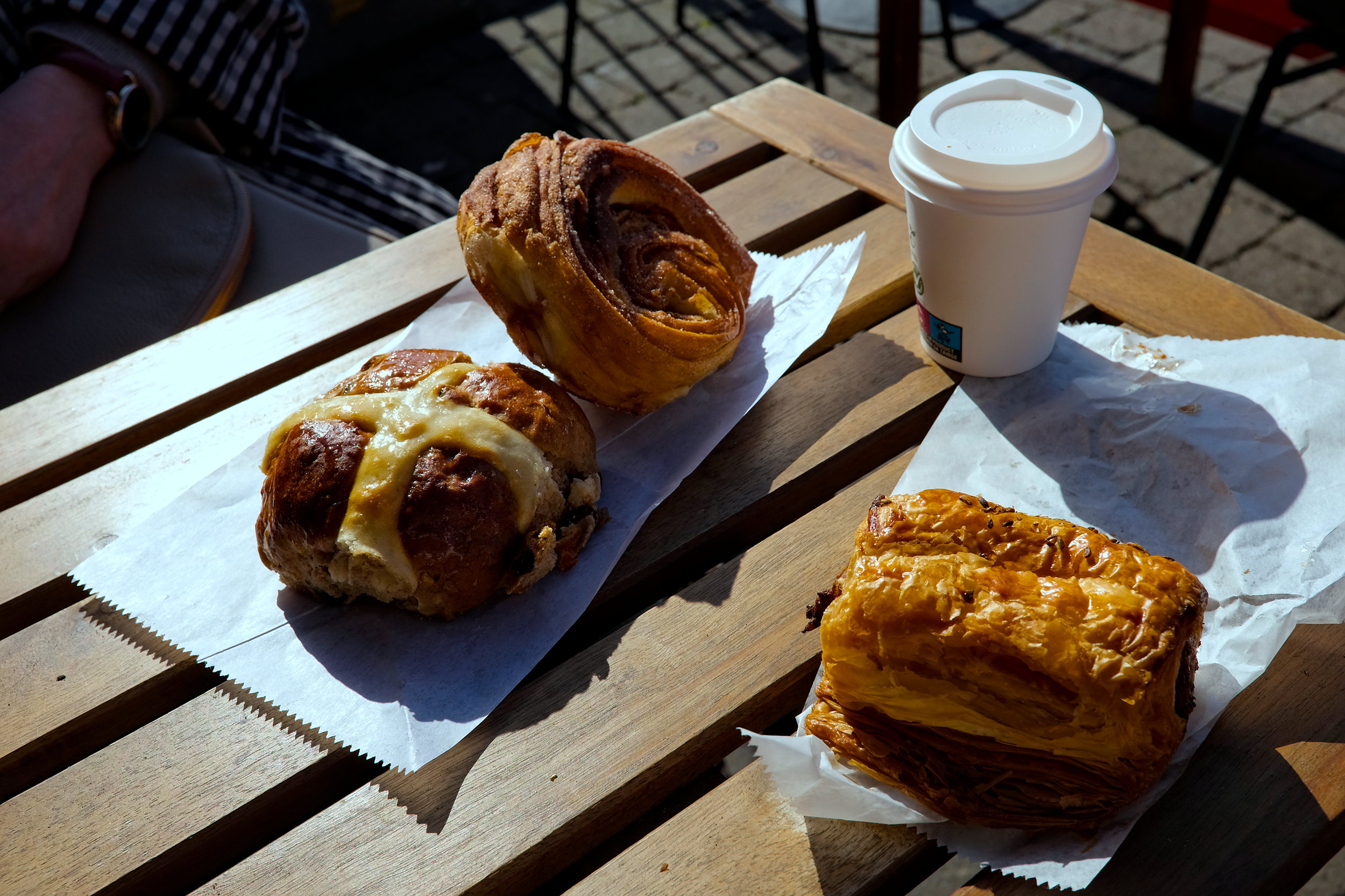 An assortment of pastries Michael and Alyssa enjoyed at Wildflour, including a sausage roll, cinnamon scroll, and hot cross bun