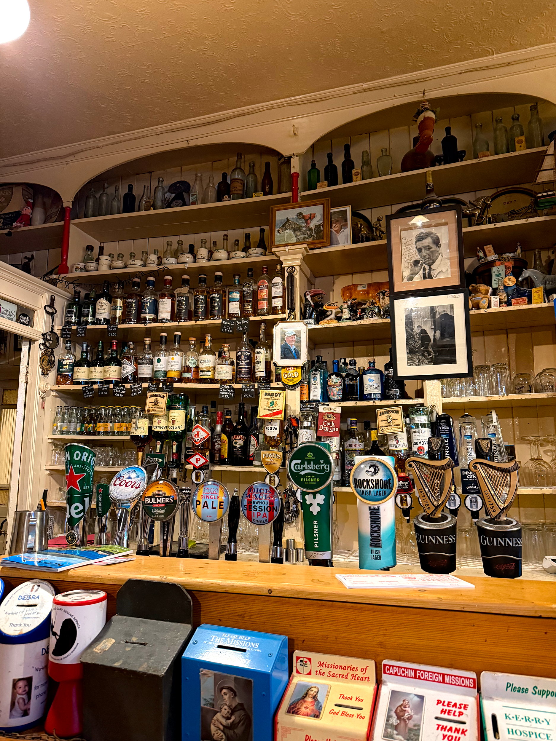 The bar inside Curran’s in Dingle, with shelves of liquor, vintage photos, and a timeless charm that reflects its local history.