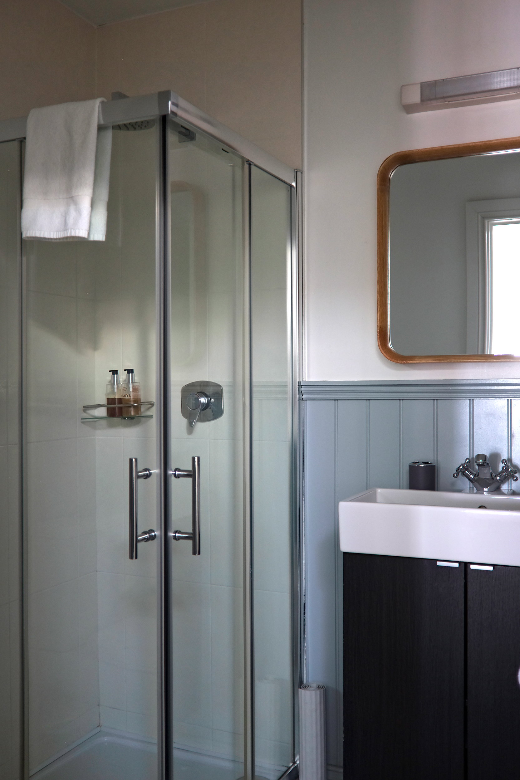 Bright, clean bathroom featuring a glass-enclosed walk-in shower, white and blue walls, and sleek fixtures.
