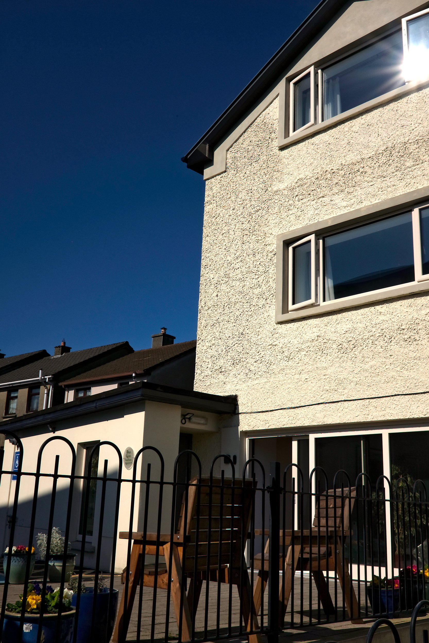 Rear of Dingle Garden Townhouse, a tidy, modern building with pale walls, neat landscaping, and a welcoming entrance.