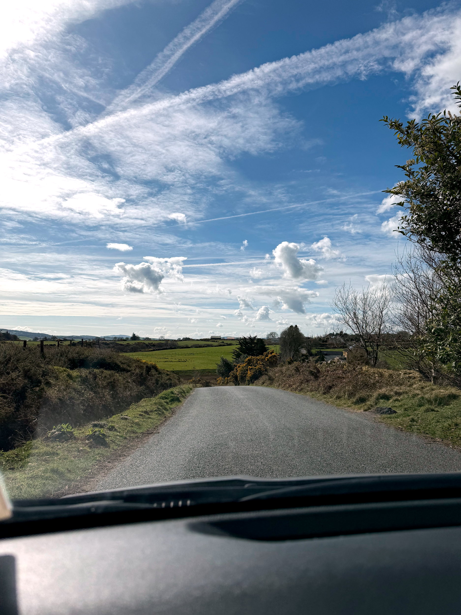 A rental car drives on a narrow road in the stunning Irish countryside