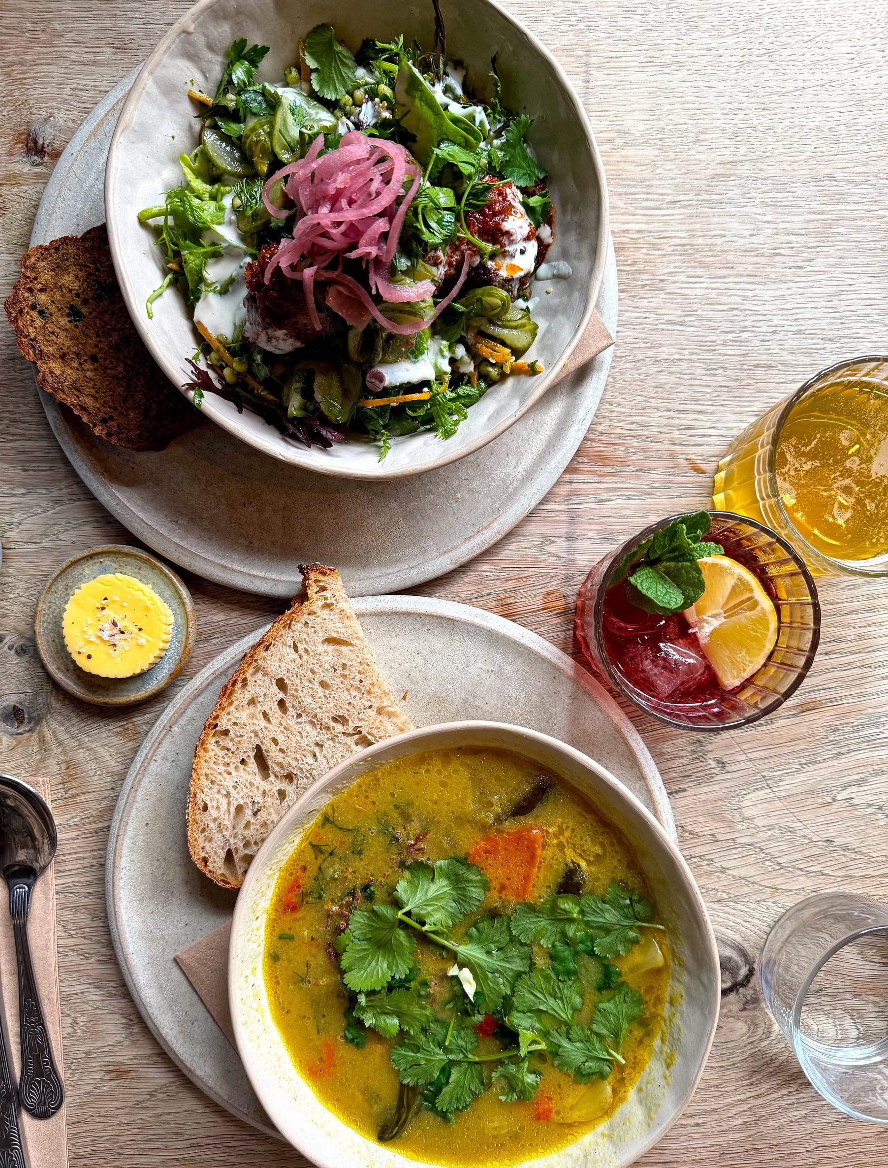 Colorful lunch spread at Kai with a vibrant lamb kofta salad topped with herbs and pickled onions, alongside a rich, coconut-based samlor kako stew filled with vegetables and warm spices.