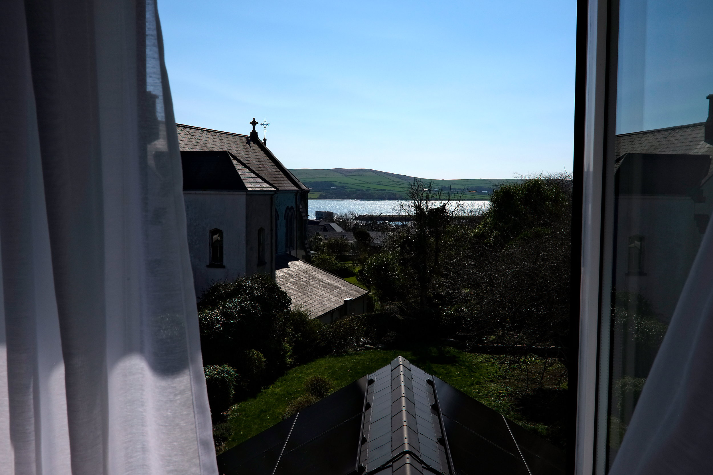 Charming view from the room’s window overlooking a lush garden, with the water and a nearby church visible.