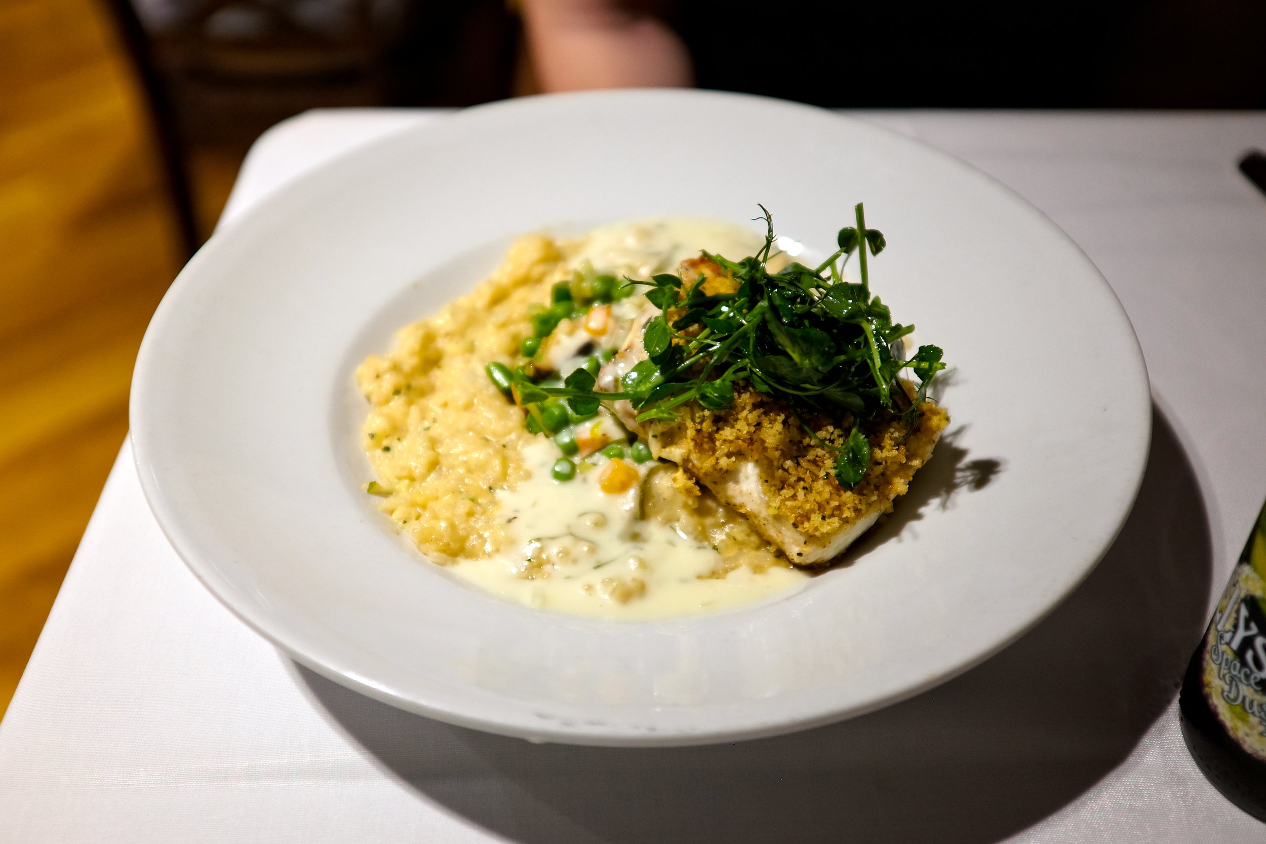 A plate of fish in a creamy sauce with risotto at Christine's Farm to Fork