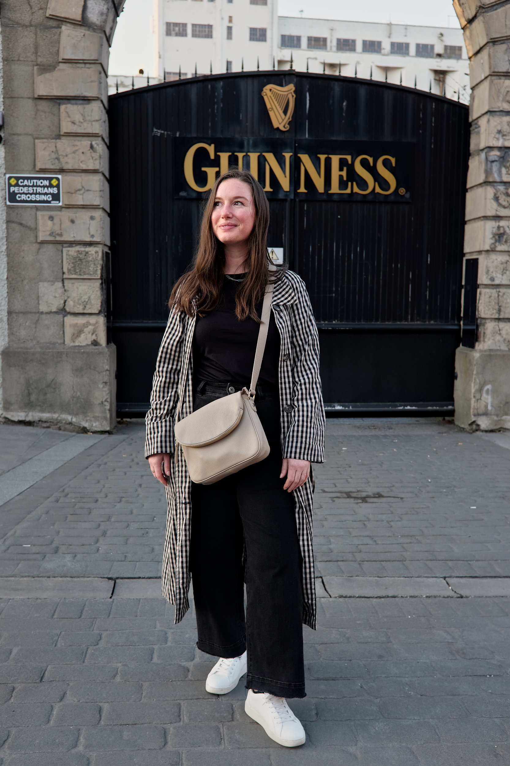 Alyssa stands in front of a gate in Dublin that reads GUINNESS with the harp logo