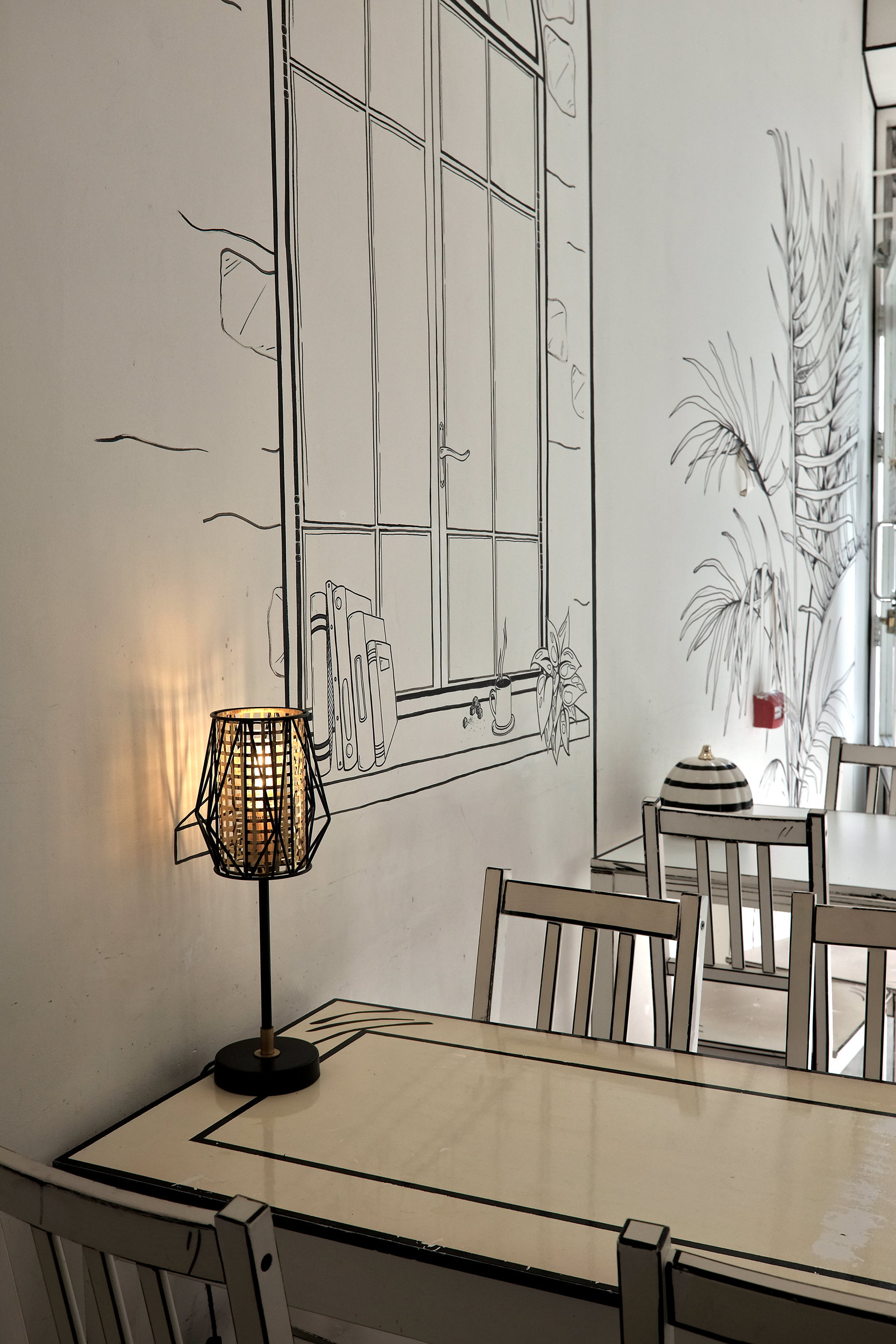 Tables line a wall in a black and white cafe that is fully hand-drawn in Dublin