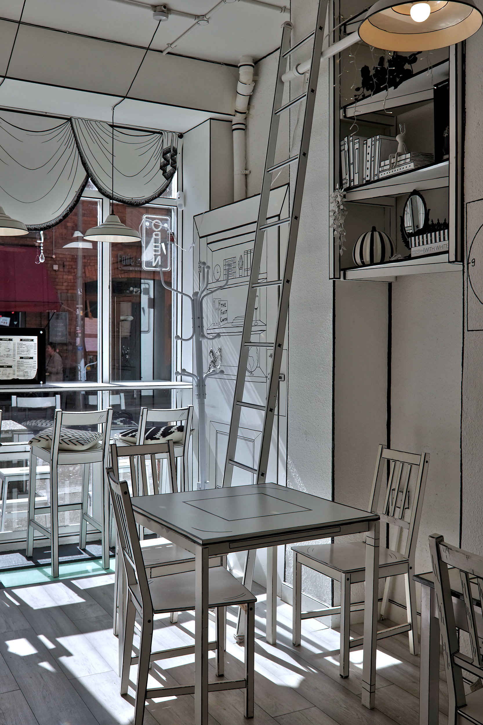 A ladder leans against the wall at First Chapter, a black and white cafe where most of the decor has been drawn onto the surface