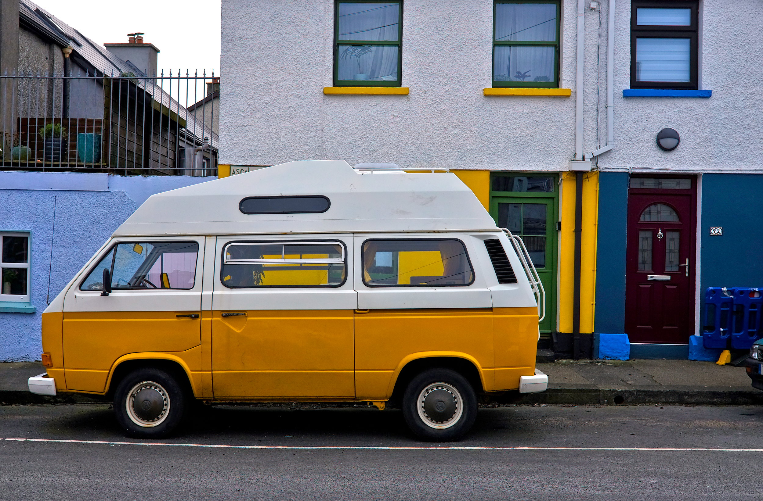 A yellow-orange van in front of equally vibrant walls in the heart of Galway