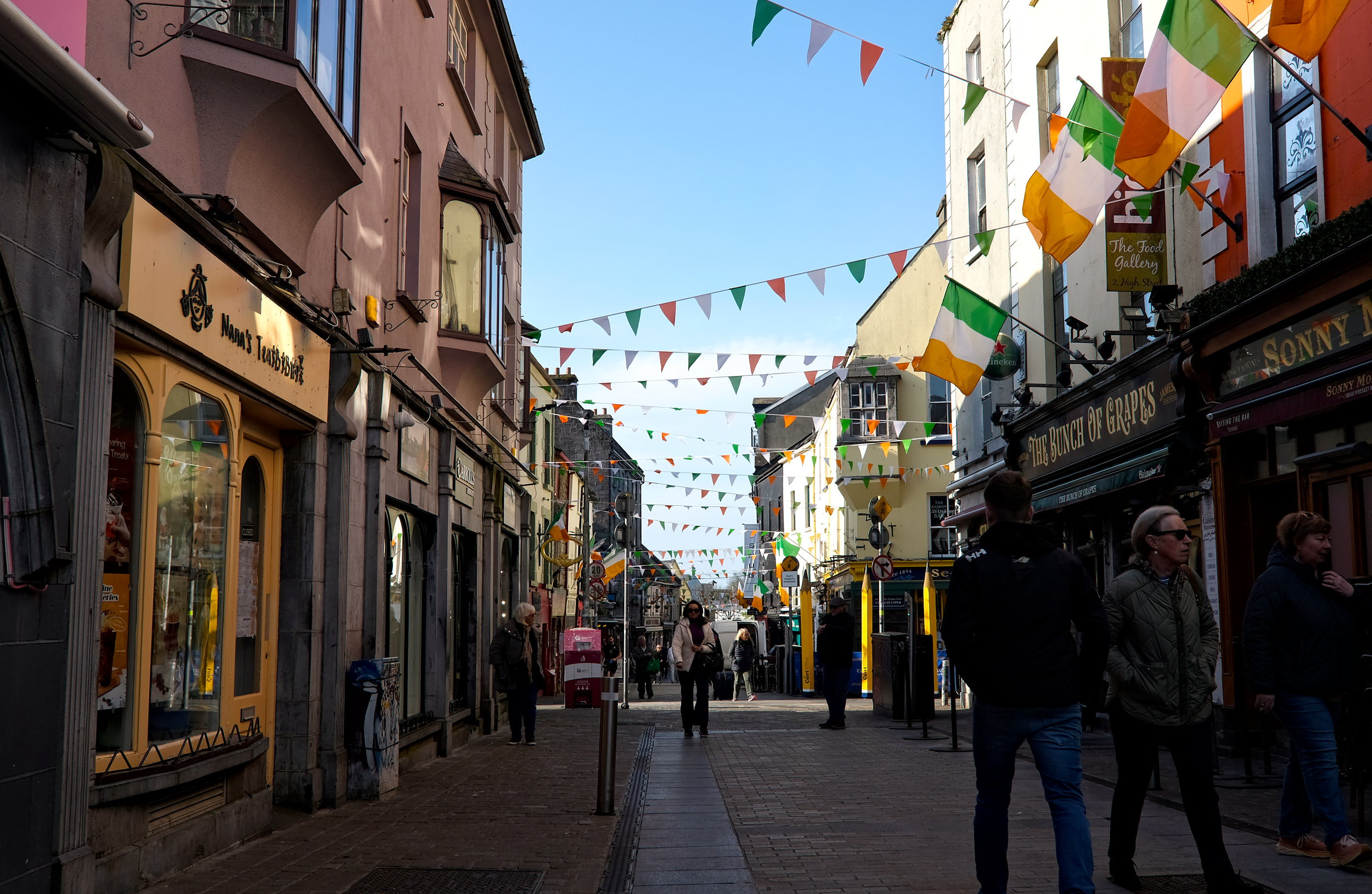 A busy pedestrian street in Galway, with Irish flags and pennant banners on display