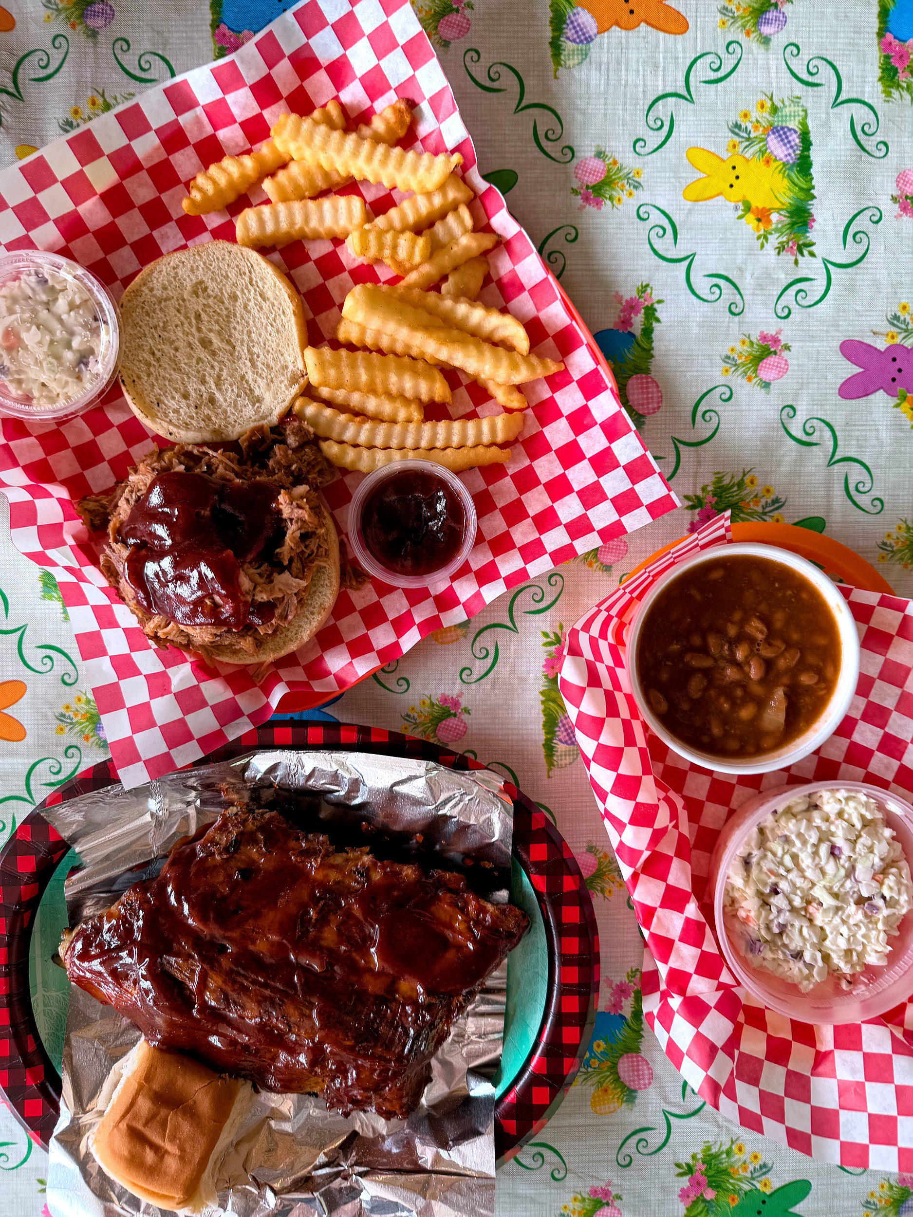A top-down shot of barbecue, including ribs, a pulled pork sandwich, and sides at Mount Carmel Cafe