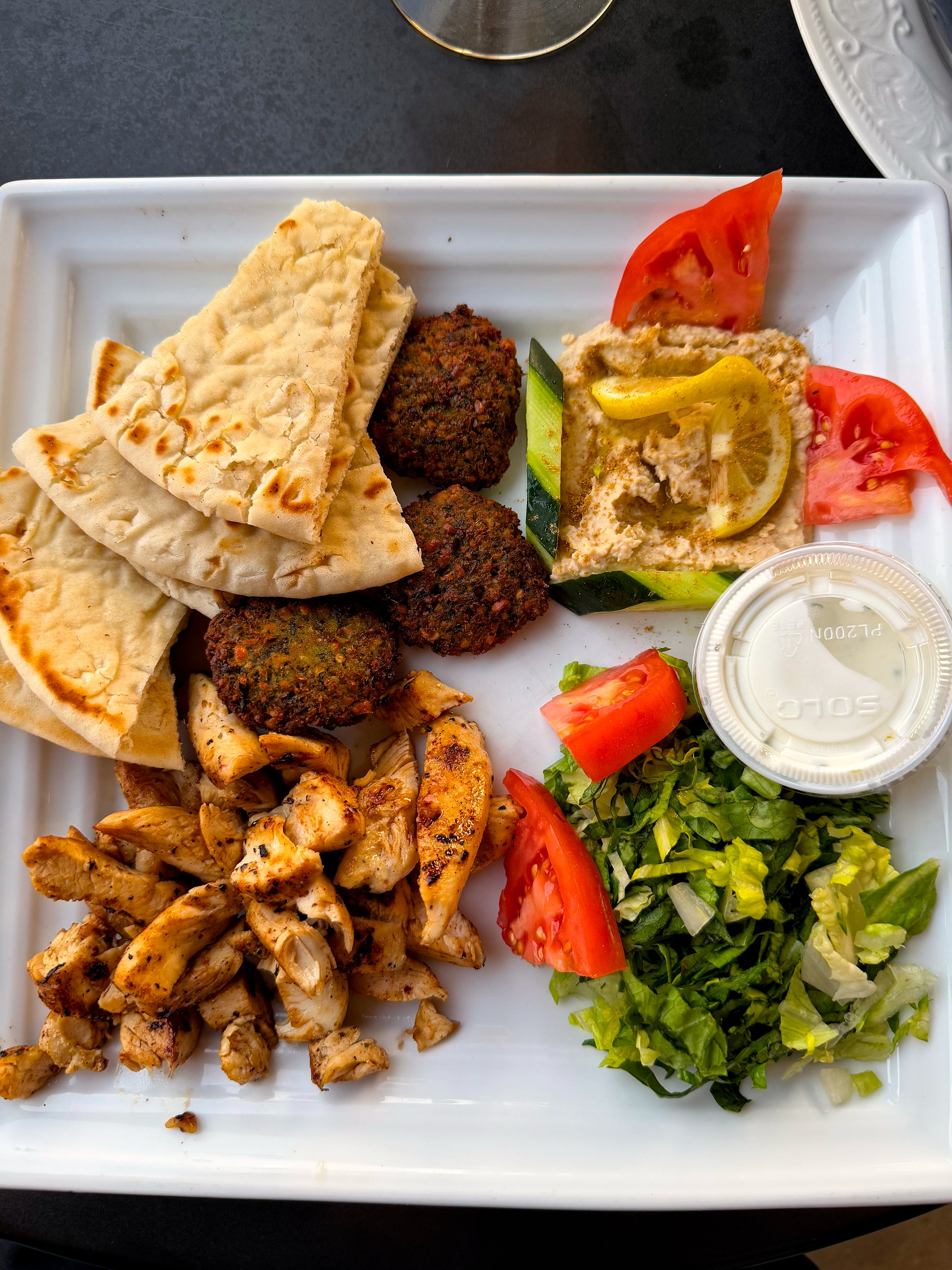 A plate of falafel, hummus, chicken, and more at Roma