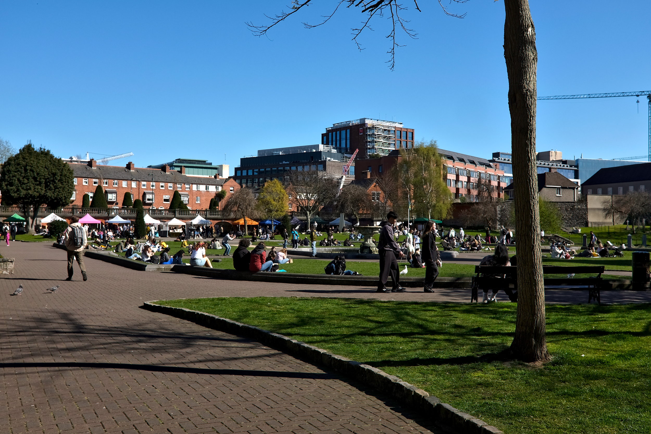 A crowd of people at St. Patrick's Park Market, with tents seen in the distance