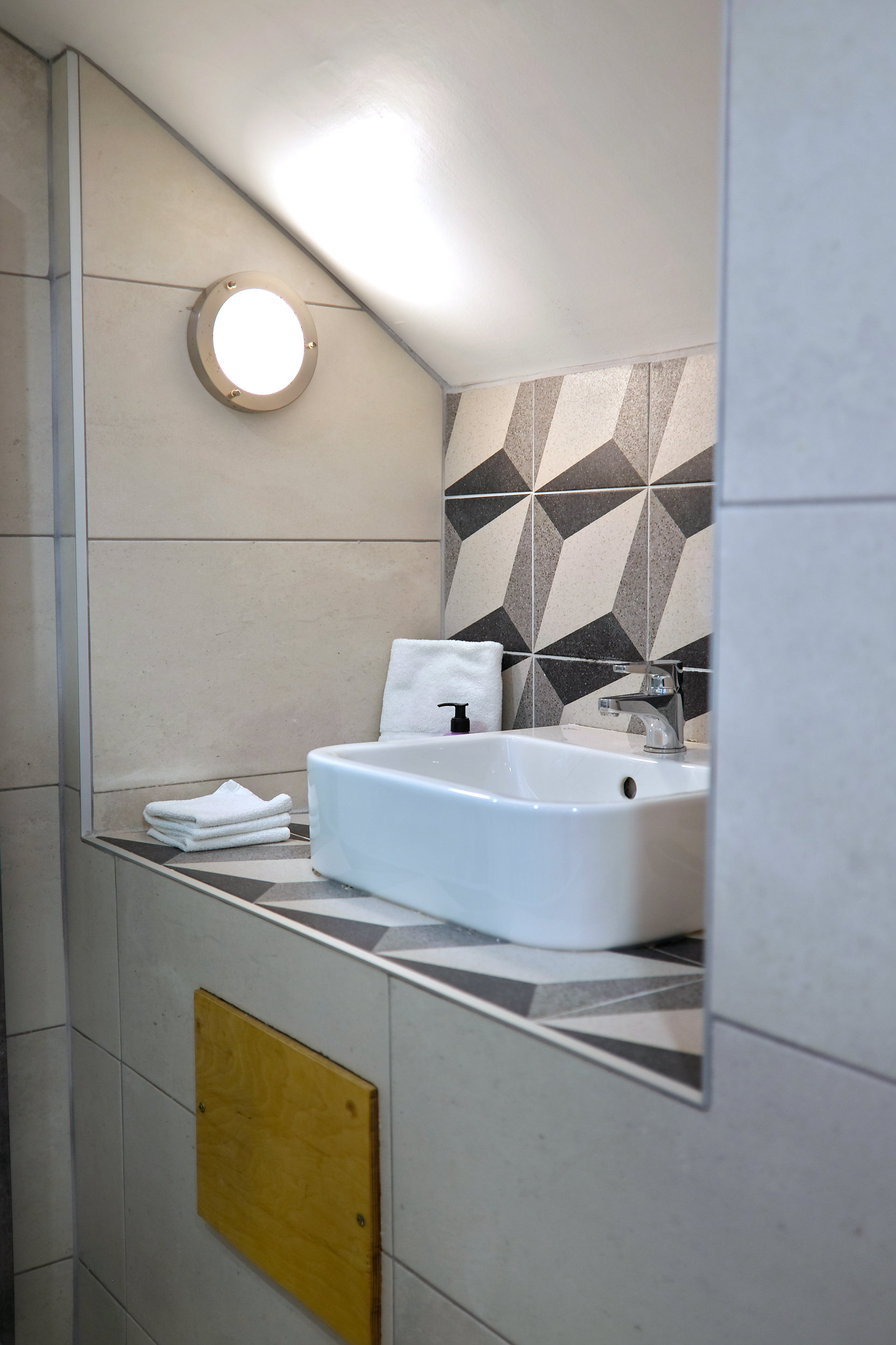 The clean and simple sink area at The Stop Galway, neatly stocked with folded white towels and a pump bottle of hand soap.