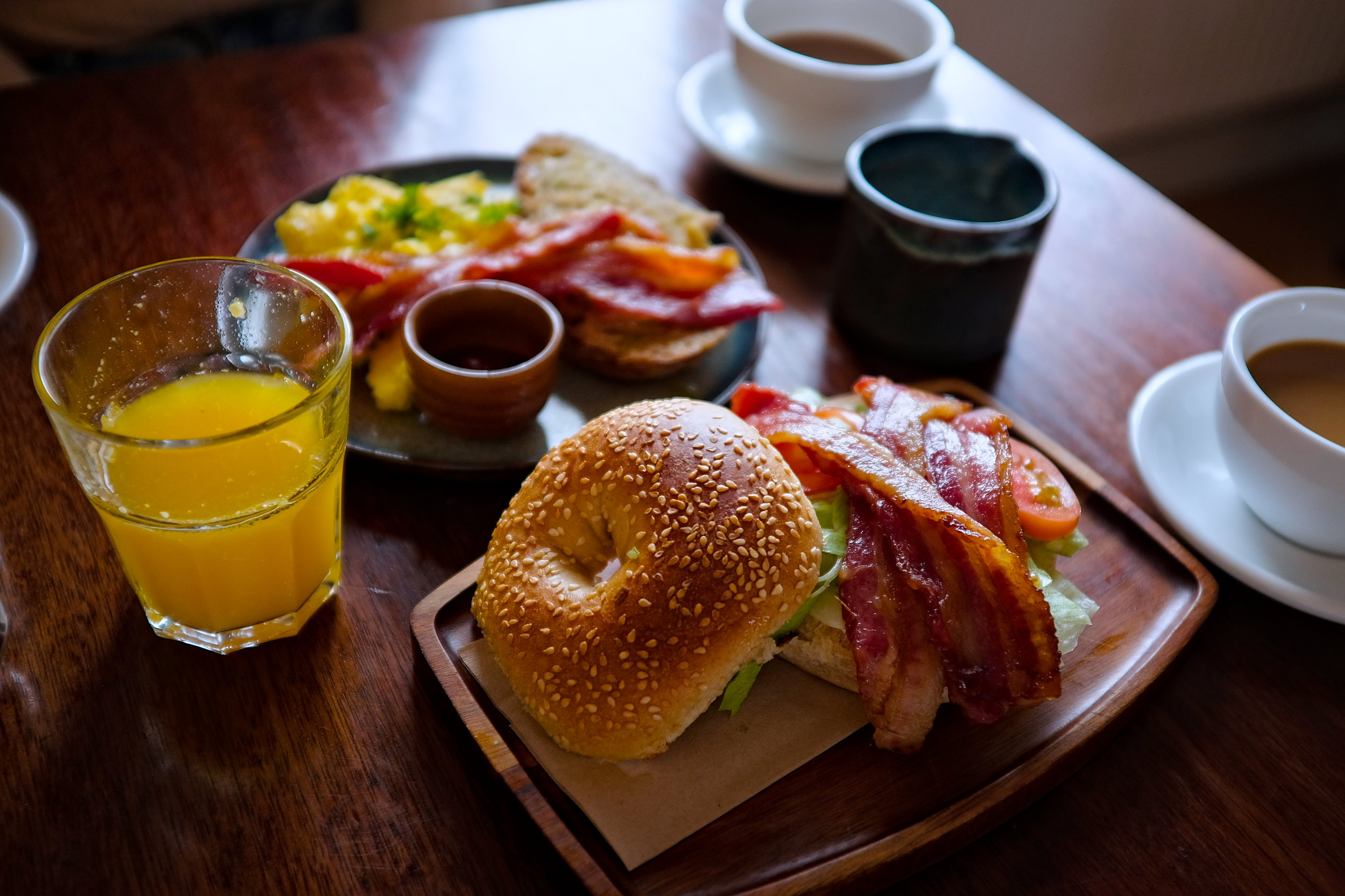 A scene from the breakfast table at The Stop, including fresh squeezed orange juice, a BLT bagel, bacon eggs, and toast, and coffee
