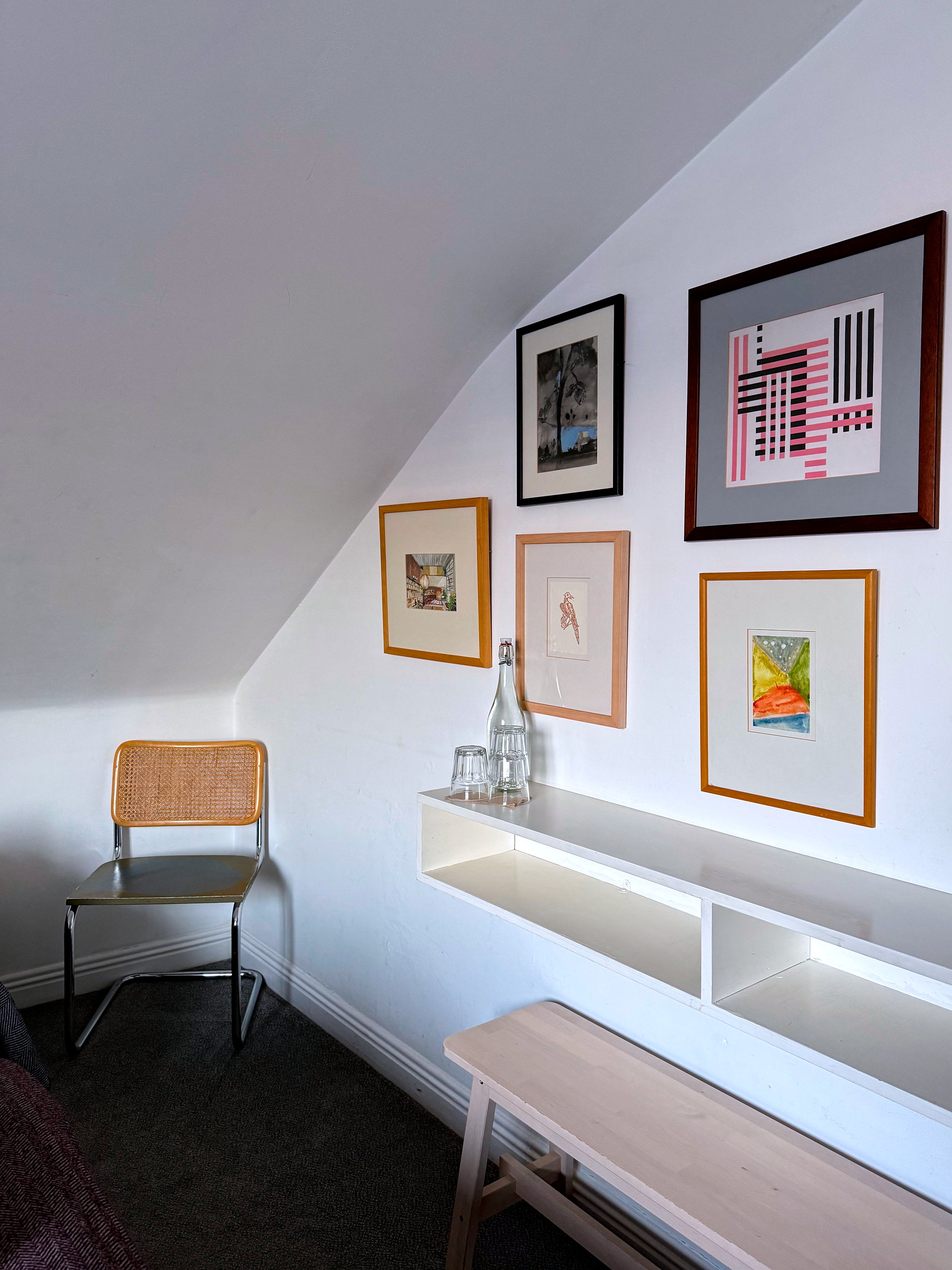 A cozy corner in the Family Room at The Stop Galway featuring a modern chair beside a bright wall adorned with colorful contemporary artwork.