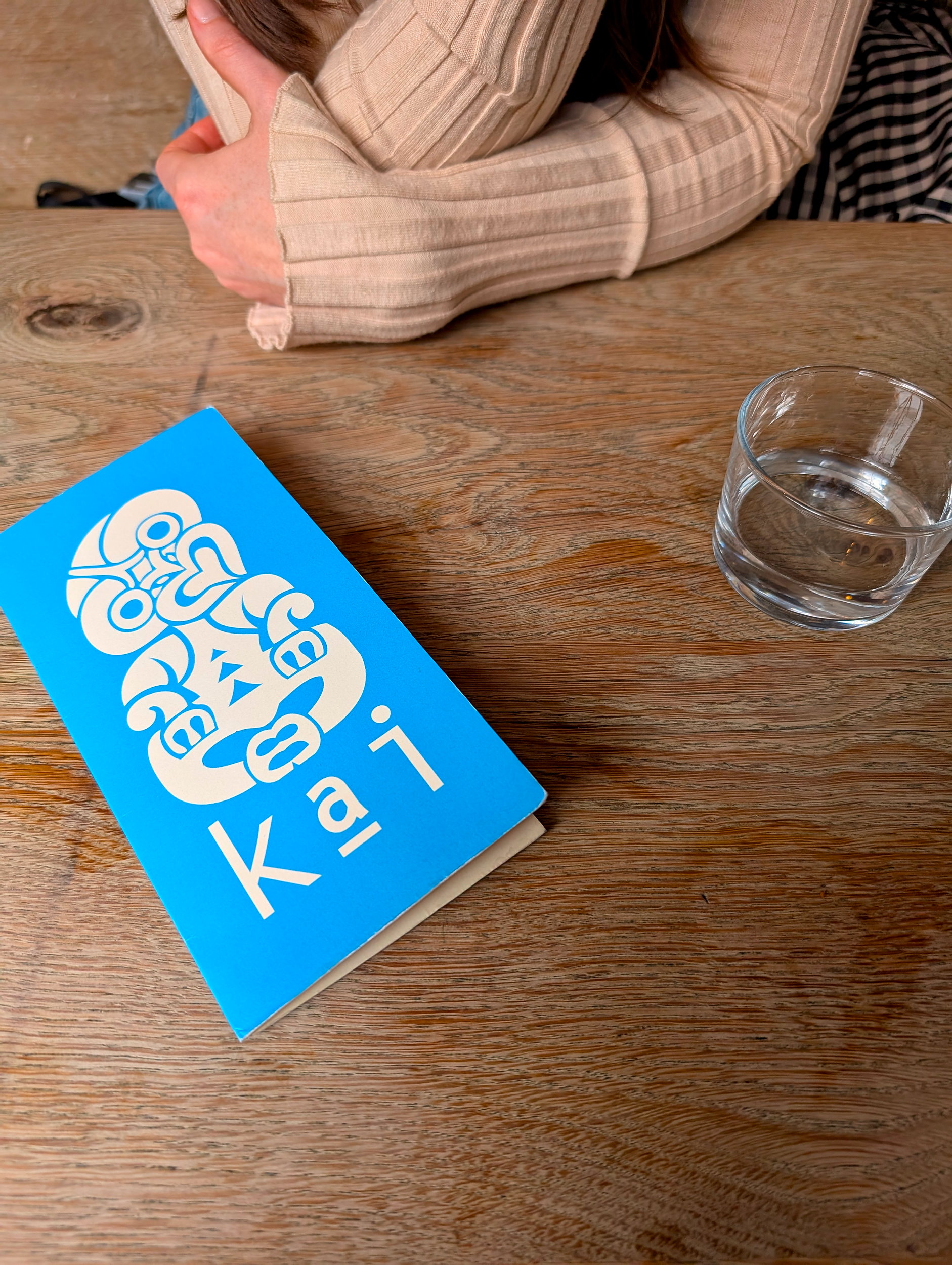 Alyssa's elbows on the table with the menu for Kai in Galway