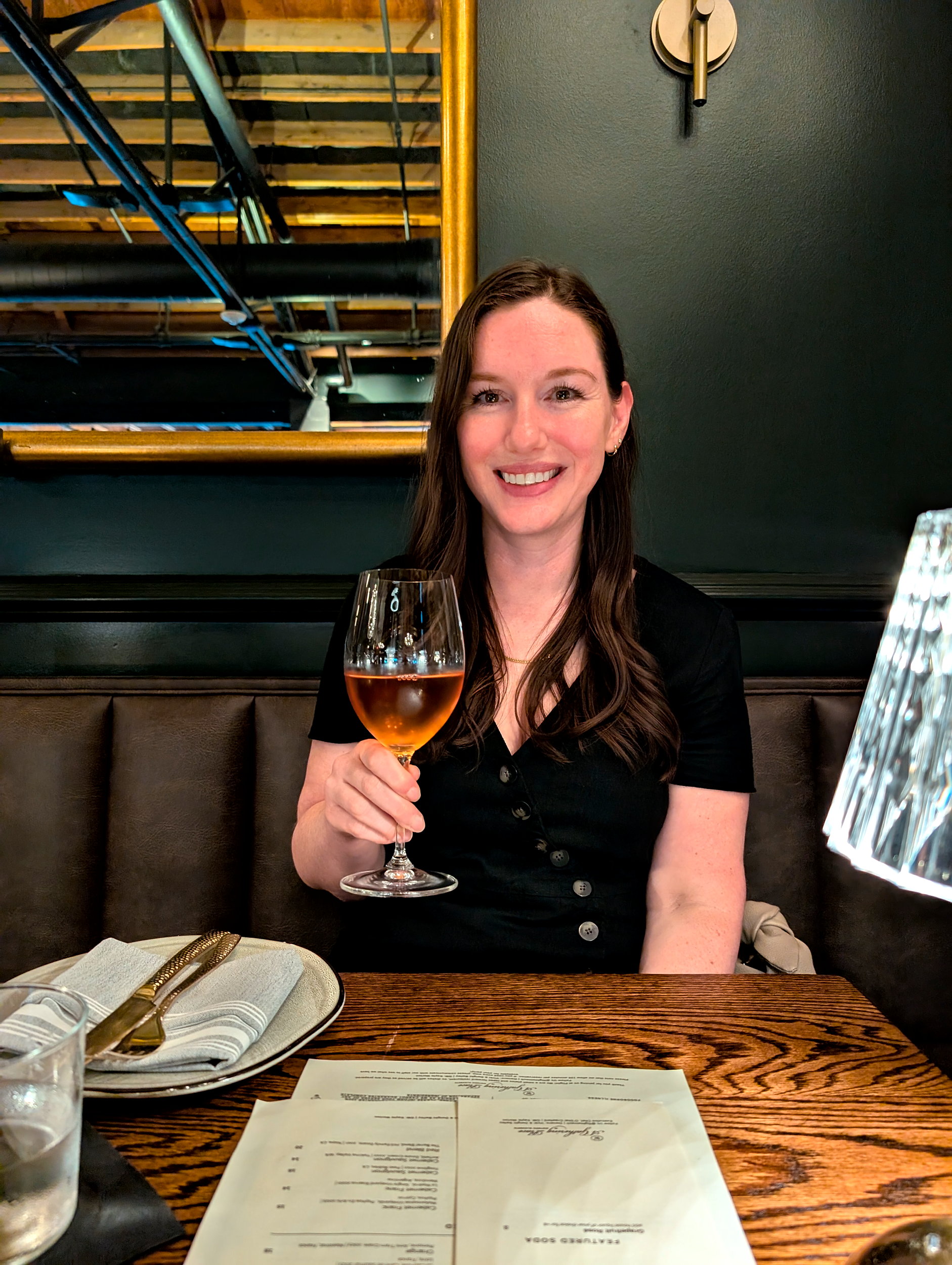 Alyssa holds a glass of wine and smiles at Flight