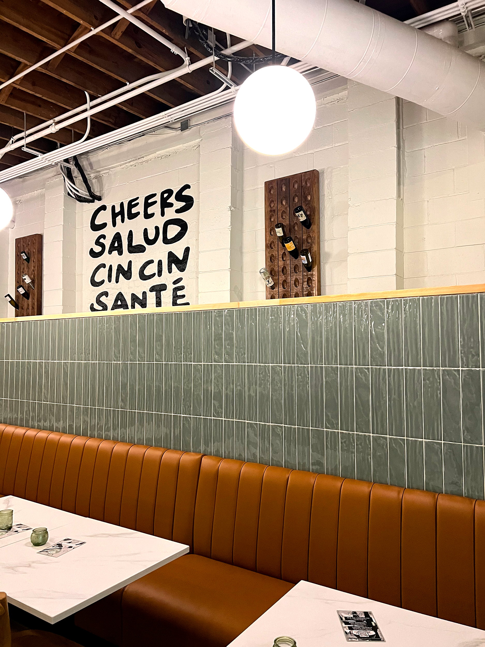 Writing on the wall of a wine bar reads "Cheers, Salud, Cin Cin, and Sante"
