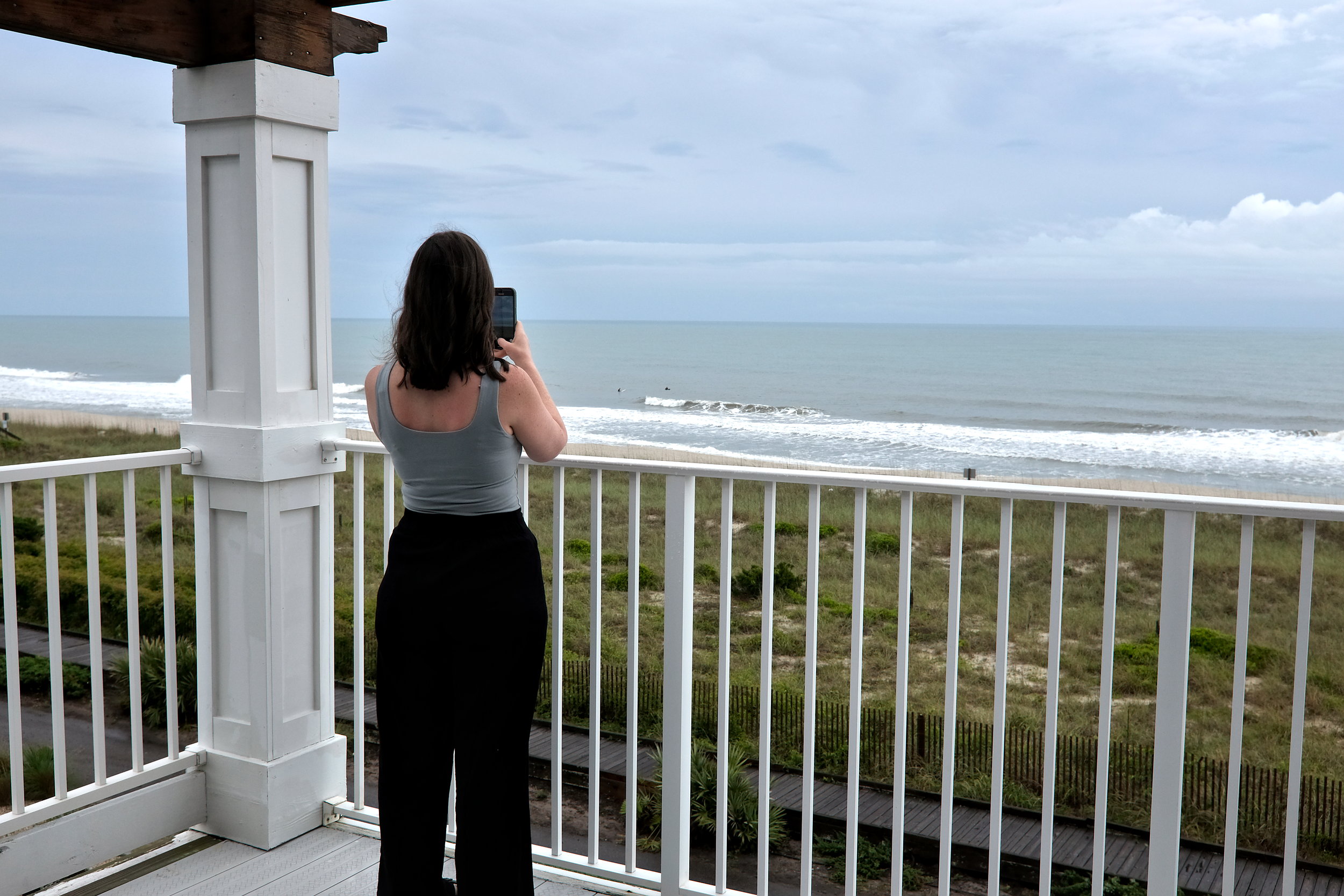 A photo of Alyssa recording two surfers at Kure Beach