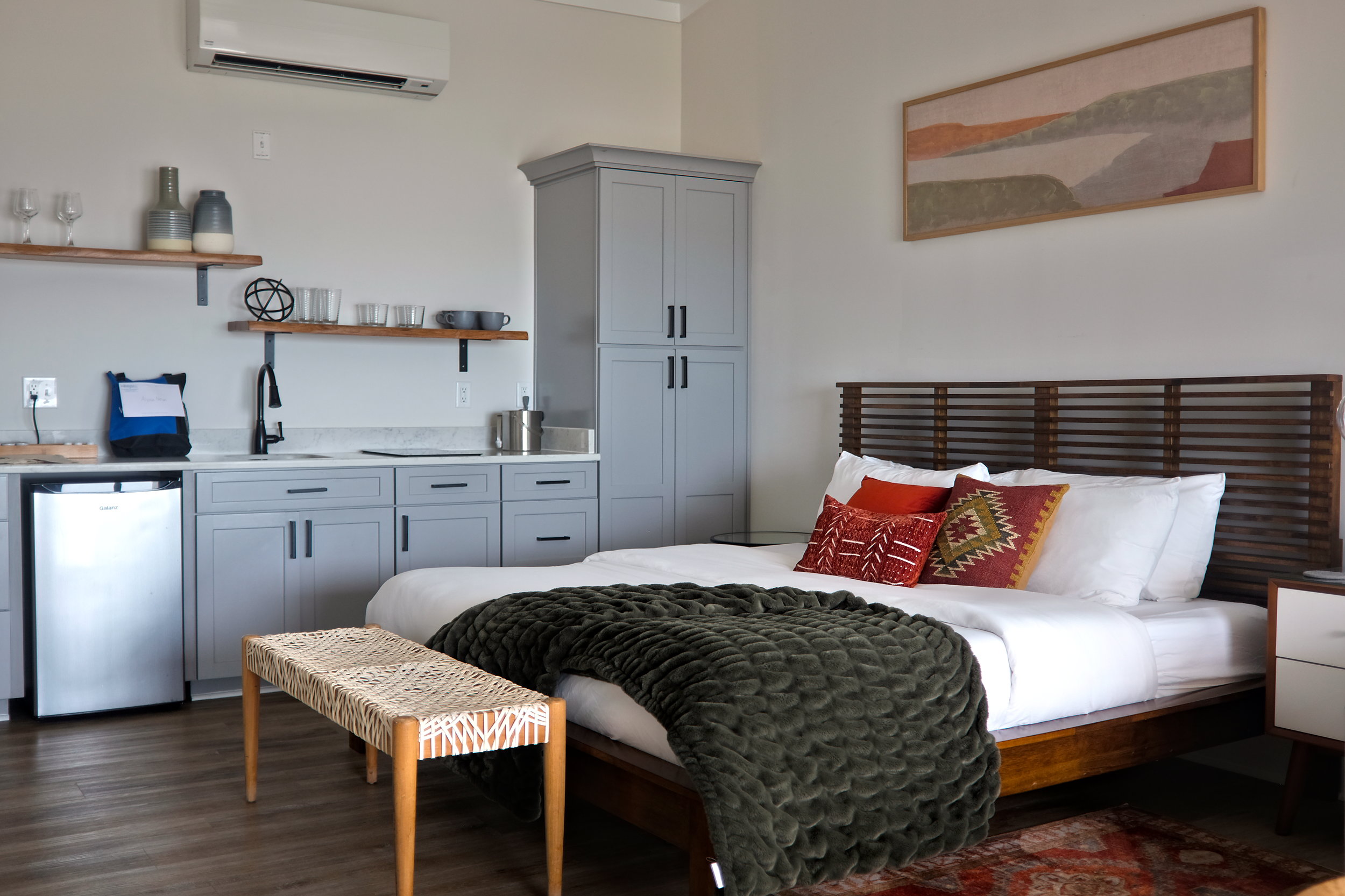 A queen bed with a kitchenette in the background at The Lighthouse at Kure Beach