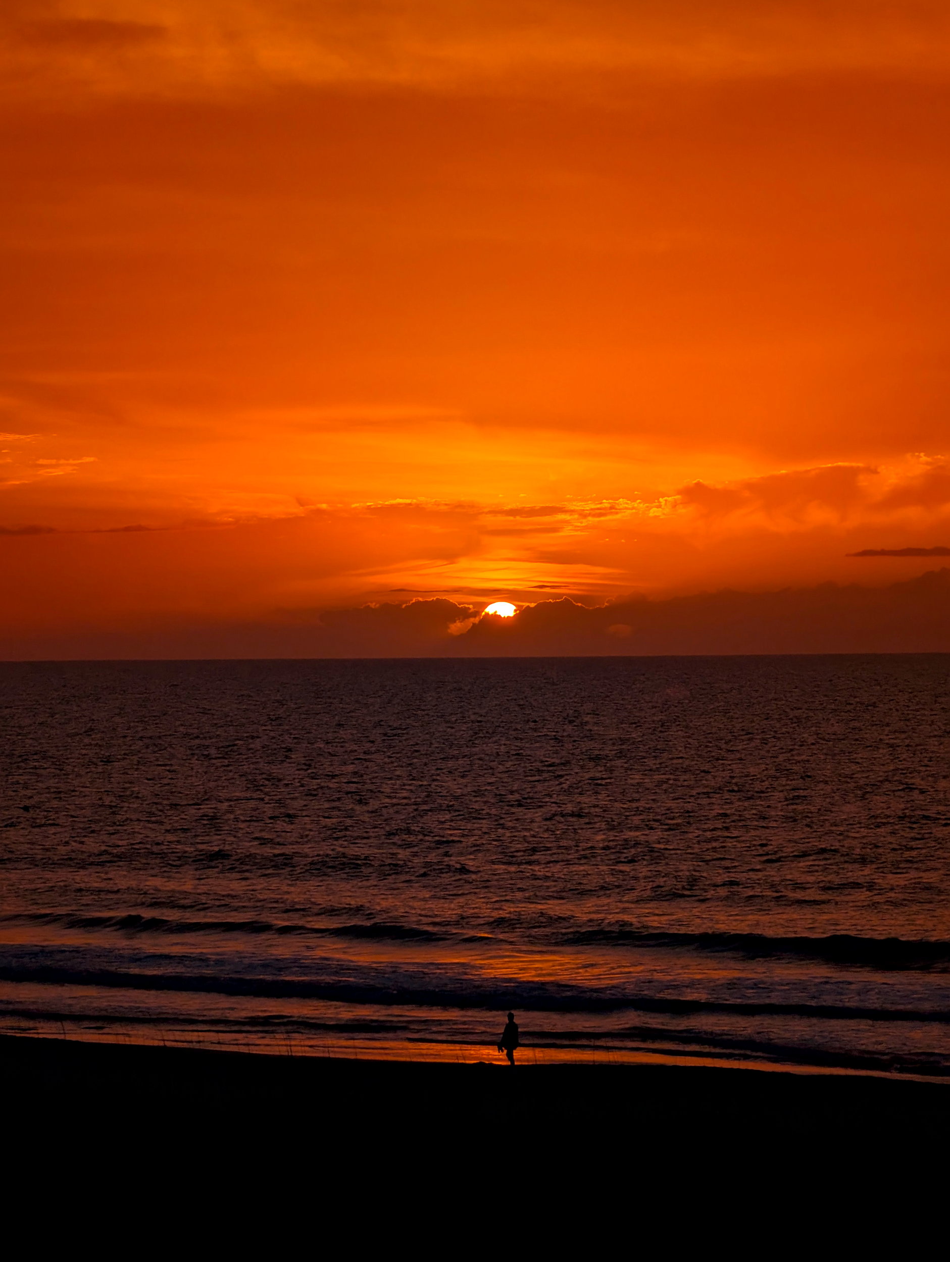 The sun rises glowing orange over the Atlantic at Kure Beach